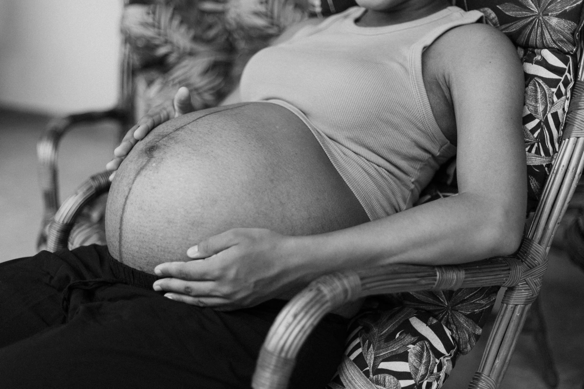 pregnant woman sitting in chair holding womb